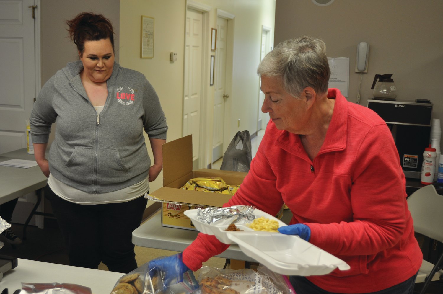 Debbie Biddle makes a container of food for Keirsten Sparks to take home to her children Monday at the Waynetown Fire Department. Free lunches can be picked up from 11:30 a.m. to 1 p.m. at the Waynetown, Wingate and New Richmond fire stations.