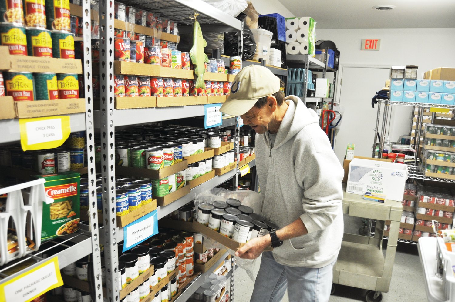 Richard Bland stocks canned goods Thursday in the FISH Food Pantry at St. Bernard Catholic Church. The pantry, like others across the area, have switched to drive-thru distribution in respond to the coronavirus (COVID-19) outbreak.