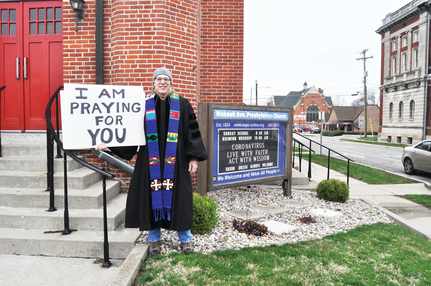 Rev. John Van Nuys, pastor of Wabash Avenue Presbyterian Church, holds a sign offering prayers Friday. The congregation has joined other local churches in suspending in-person worship services during the coronavirus (COVID-19) pandemic.