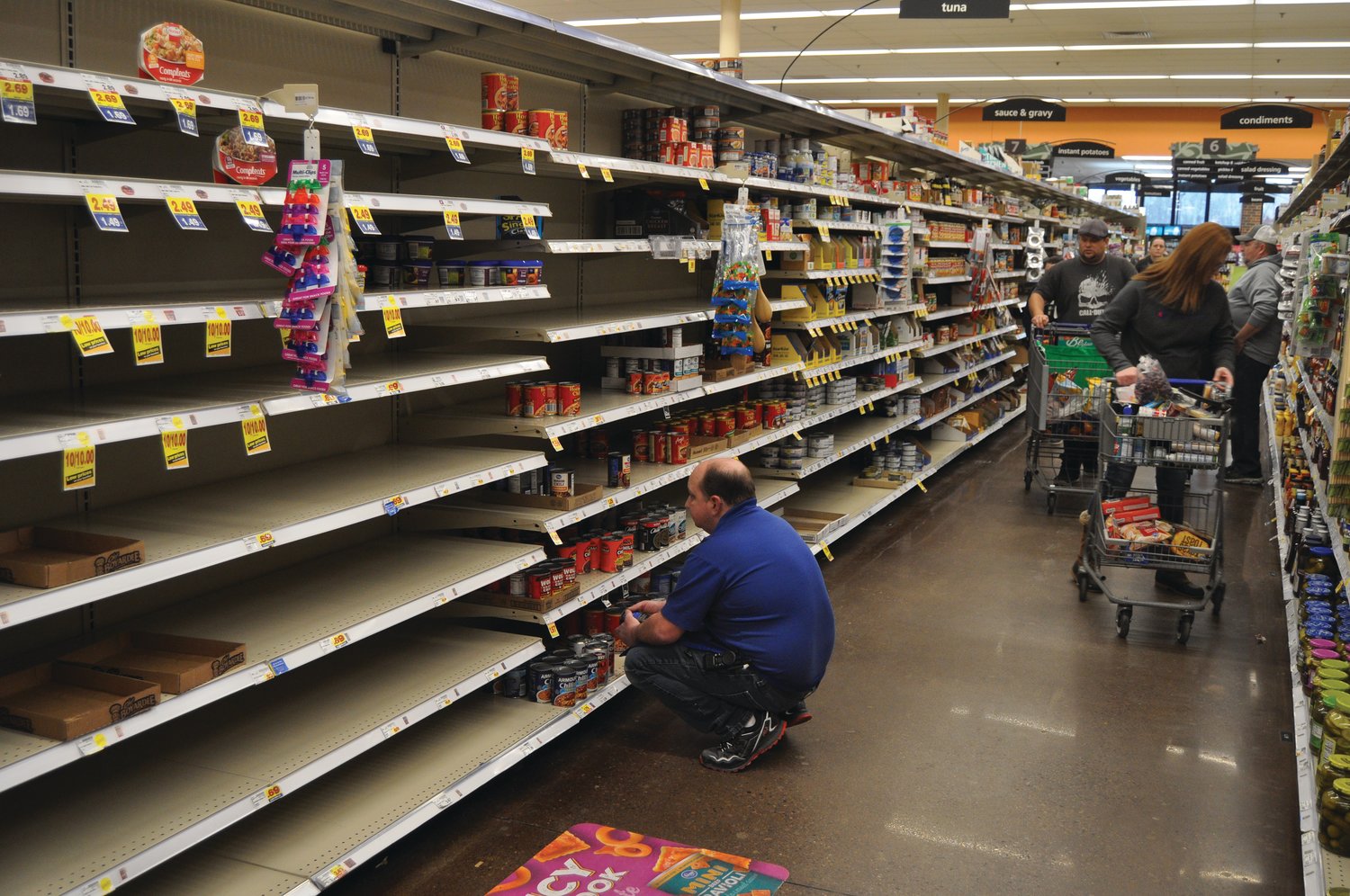 Shoppers browse the canned food aisle Monday at Kroger. Grocery stores can remain open during the statewide, two-week "stay-at-home" order taking effect just before midnight tonight.