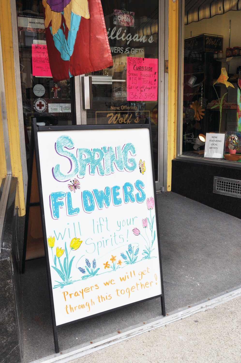 A sign in front of Milligan's Flowers & Gifts encourages customers as businesses prepared for the state's two-week stay at home order, which took effect just before midnight Wednesday.