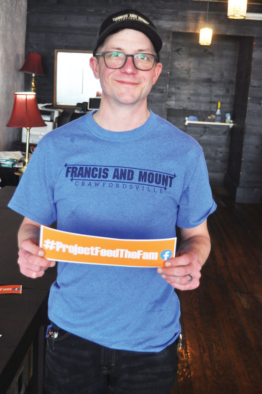 Isaac Weliver, owner of Francis & Mount, shows one of the bumper stickers promoting the #ProjectFeedtheFaM that are available for sale. The restaurant has fed more than 300 people through donated meals with support from local businesses.