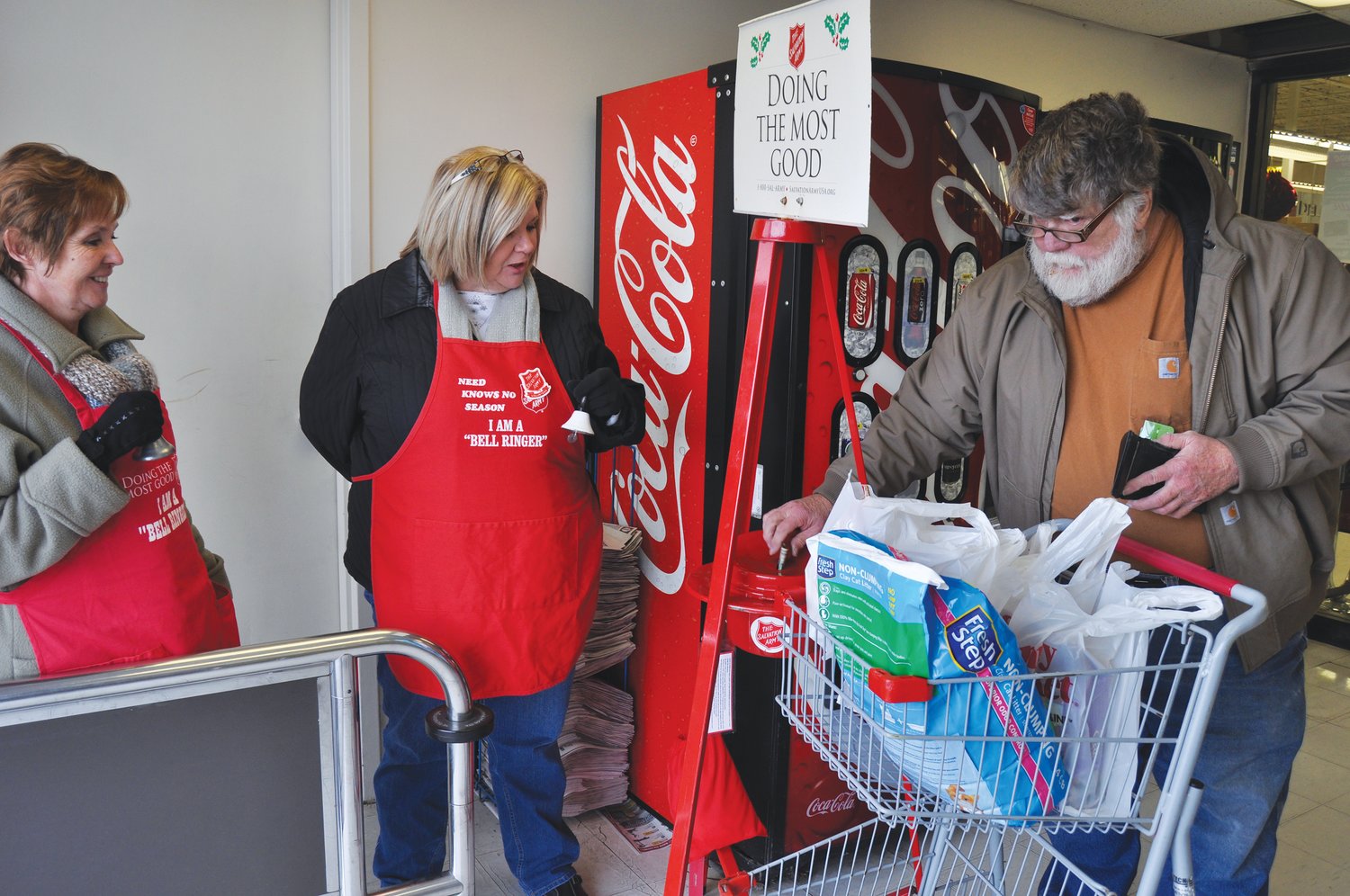 Jasper Cox puts cash in the Salvation Army Red Kettle at County Market, as bell ringers Faye Cooksey and Sandy Webb look on during the 2017 kettle campaign.