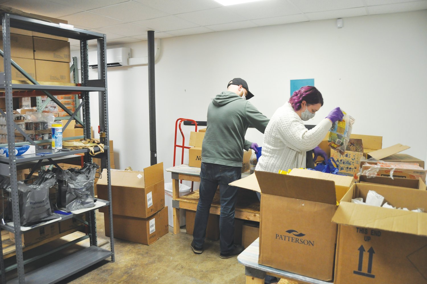 Kelsey Norris and her husband, Matt, pack bags of food for the Nourish program Thursday at the Montgomery County Youth Service Bureau. Local companies and organizations have stepped in to keep the program running during the school closures.