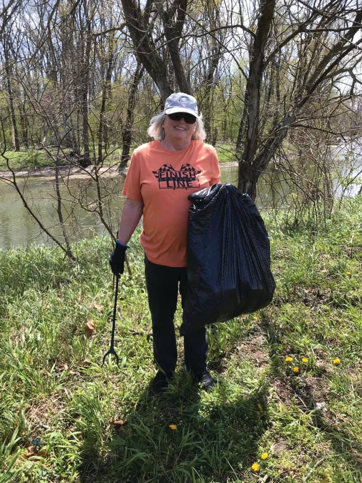 Cindy Woodall, executive director of Friends of Sugar Creek, picks up trash along the creek. Participants are encouraged to take a photo of themselves during the clean up and email the image to canoe@friends
ofsugarcreek.org to receive a T-shirt.