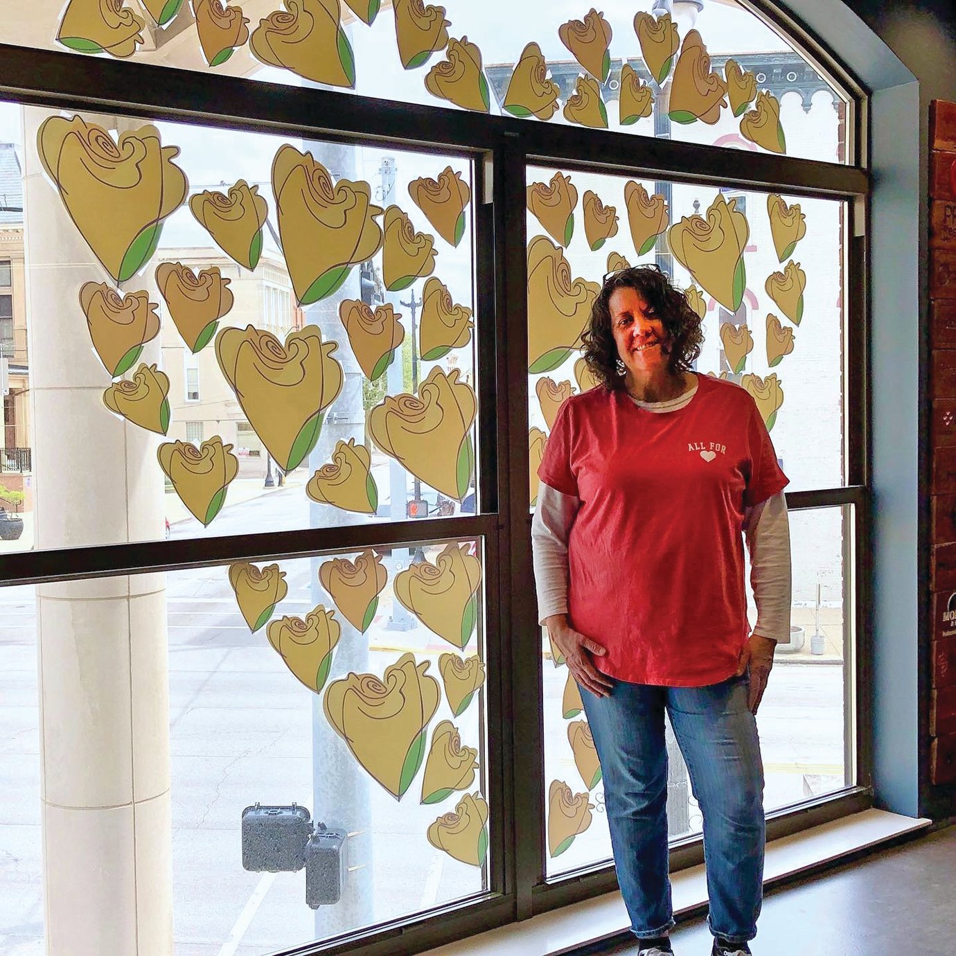 Local artist Nina Cunningham completes her heart-shaped design of yellow roses April 26 on the second floor of the Fusion 54 building to show support for small businesses around Crawfordsville.