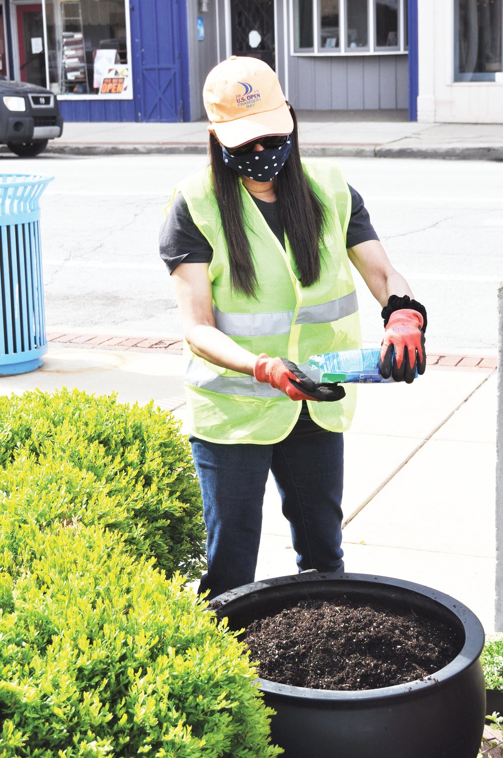 Marie Stocks pours a handful of water storing crystals Monday for a planter at Marie Canine Plaza. Crawfordsville Main Street members filled the planters at the plaza.