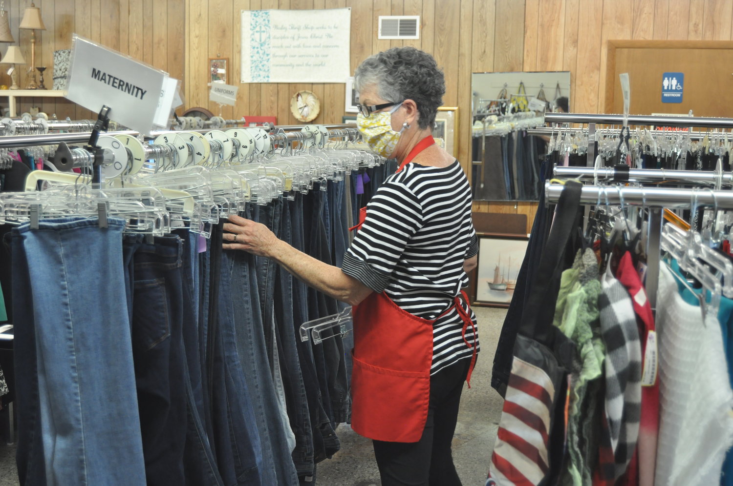 Volunteer Karen Biddle sorts through blue jeans Wednesday at the Wesley Thrift Shop. The store, a ministry of First United Methodist Church, reopened to customers this week with restrictions to limit the spread of the coronavirus.