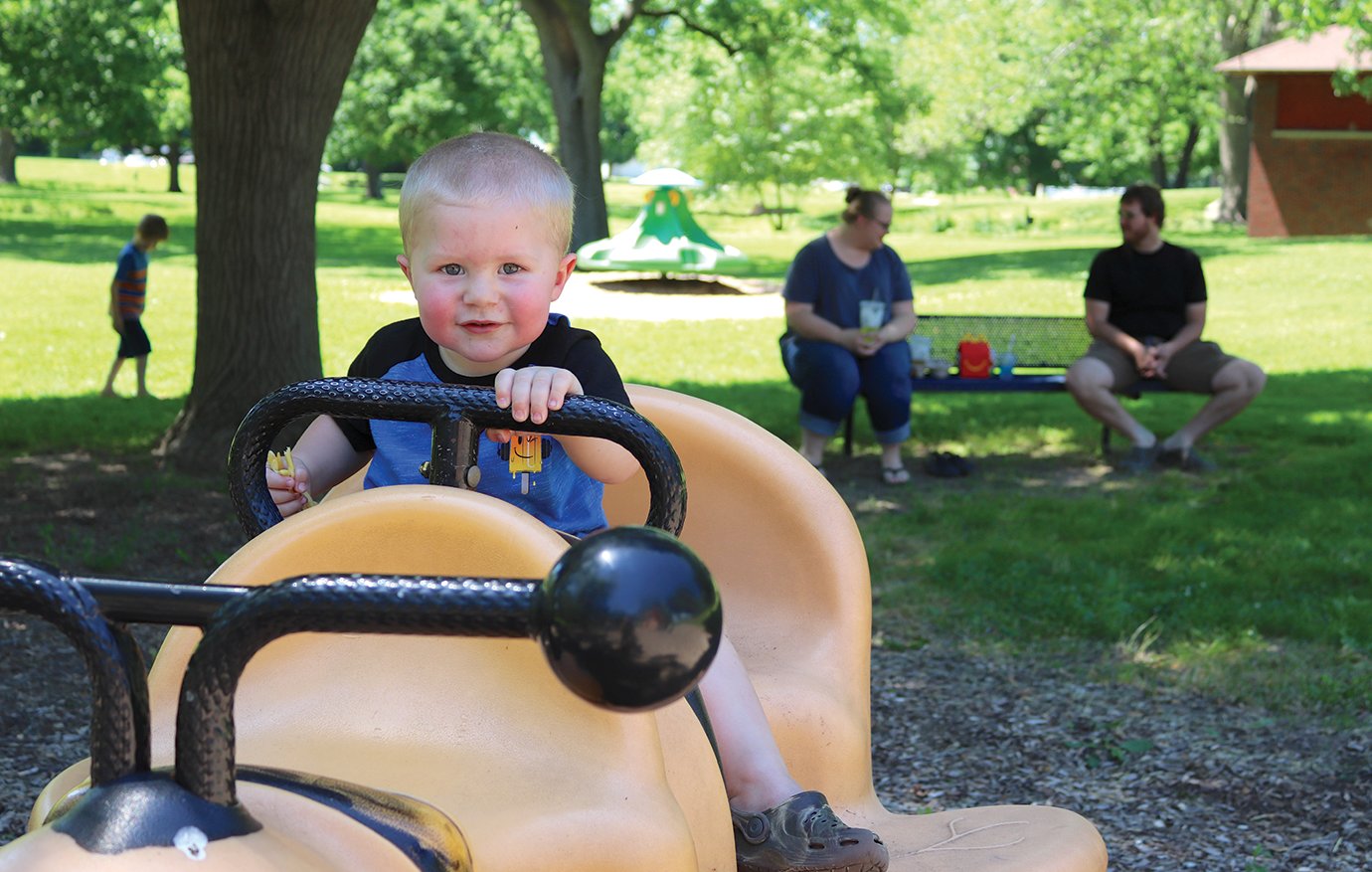 Toddler Jackson Drolinger plays on the rocking-bee Friday at Milligian Park with parents Michael and Heather close by.