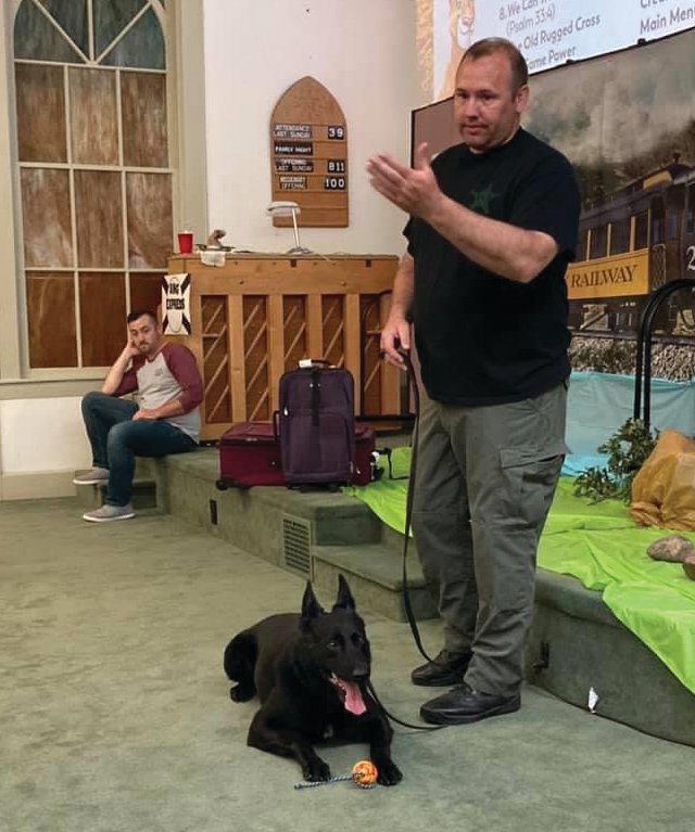 Montgomery County Sheriff's Sgt. Kevin Crull, joined by K-9 officer Demon, gave a presentation last week to the Vacation Bible School at Parkersburg Christian Church, as Pastor Cody Hargis watches. The church presented a $400 check to the K-9 unit with money collected from the children, VBS leaders and the church's missions fund.
