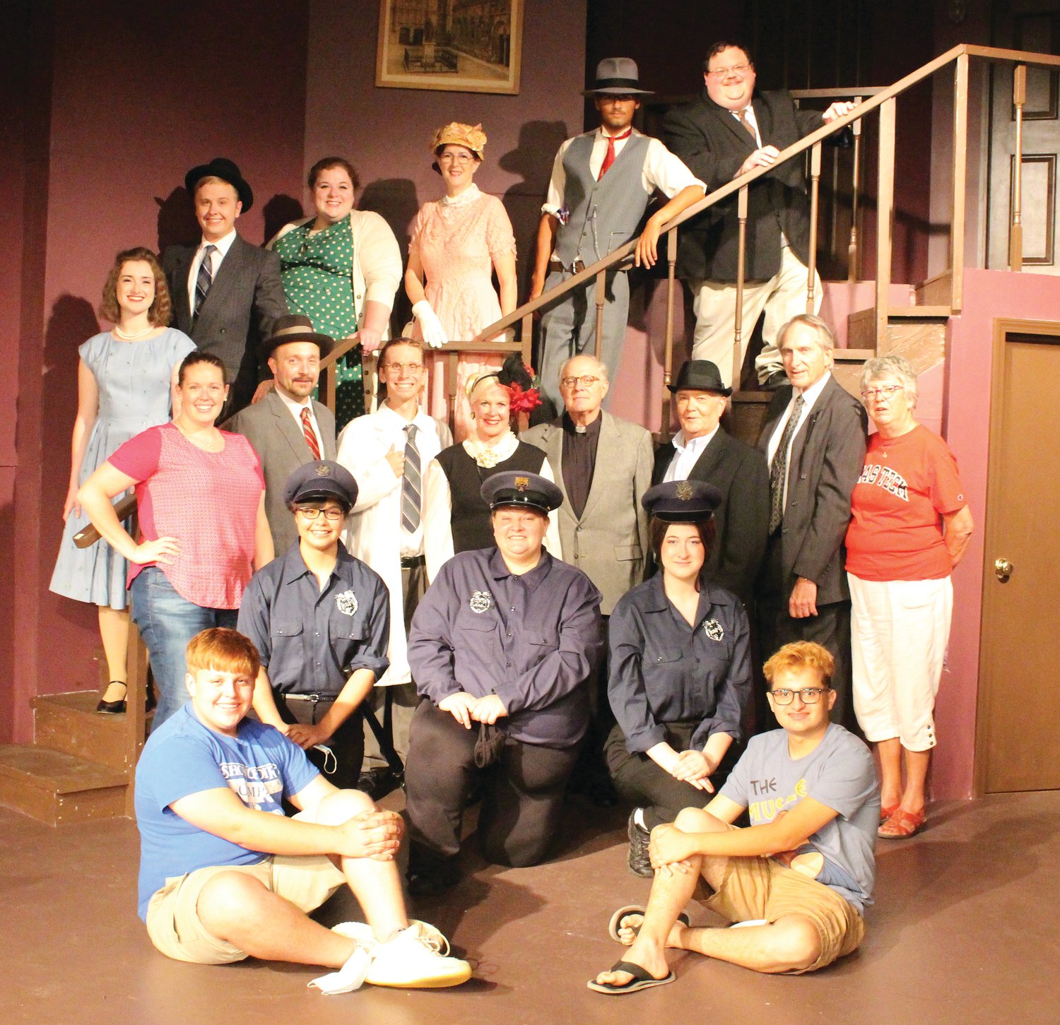 Members of the cast for Arsenic and Old Lace, are, from left, front row, Harmon Hann and Ross Tunin (both techs); second row, Alecsandra Baldwin (Officer Brophy), Lora Burris (Officer O’Hara), Nicole Hays (Officer Klein); third row, Katie Melvin (director), Adrian Burris (Mr. Gibbs), Alan Hobson (Dr. Einstein), Carol Homann (Mrs. Harper), Kurt Homann (Rev Dr. Harper), Kenn Clark (Mr. Witherspoon), Keith Strain (Lt. Rooney), Betsy Strain (producer); and on the stairs, Michaela Semak (Elaine Harper), Mike Melvin (Mortimer Brewster), Mary Taylor (Abby Brewster), Cheri Clark (Martha Brewster), Isaac Bacon (Jonathan Brewster) and Dan Martin (Teddy Brewster).