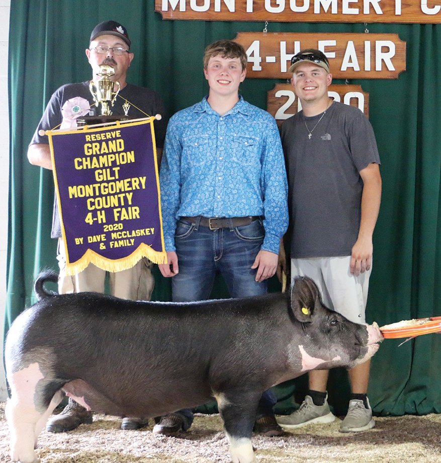 Don Martin, from left, Collin Martin and Brinton Sieferman pose for a quick photo in front of the 2020 Montgomery County 4-H Fair backdrop following an award presentation in which Collin received Reserve Grand Champion Gilt for his animal.