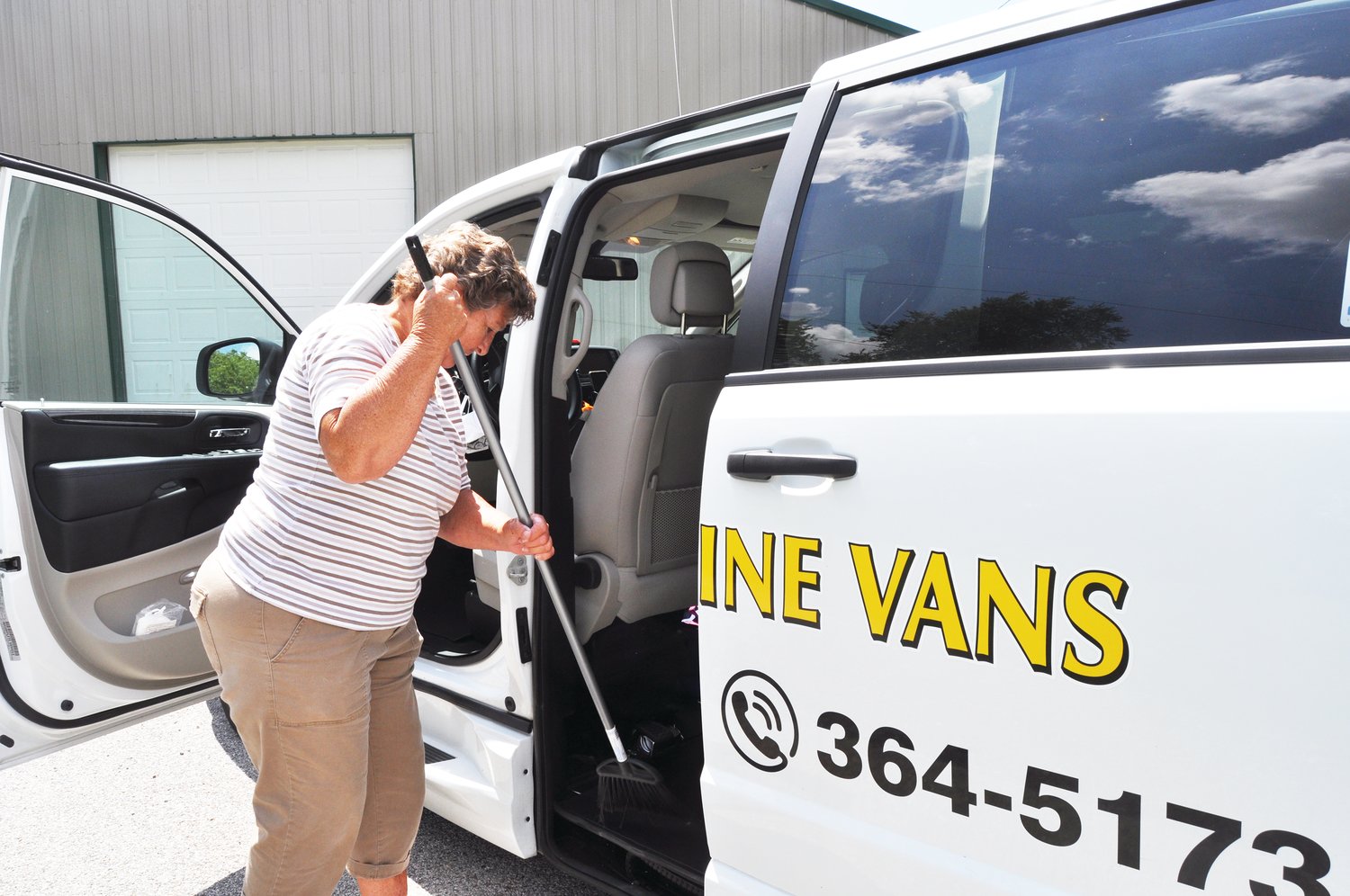 Roben Epps, lead driver for the Sunshine Vans program, sweeps out a van Friday in Milligan Park. The program is adding two new vans to its fleet through state and federal funding.