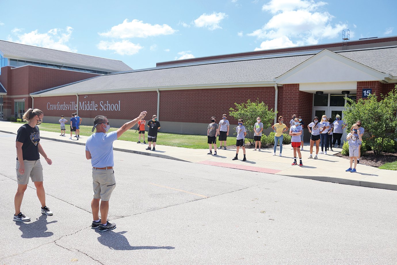 Physical education teachers Amanda Elizonzo and Andy Craig, left, instruct a seventh-grade class to warm up for a game of cardio softball by walking around the south parking lot at Crawfordsville Middle School. Student would run and walk for 20 seconds at a time to get loose and enjoy an outdoor break.