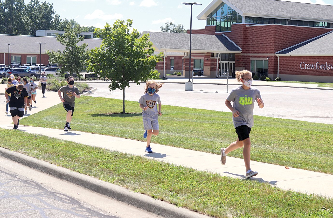Henry Hartnett and Stormy Earls, front, head into the 20-second running portion of a couple warmup laps around the Crawfordsville Middle School parking lot Tuesday during physical education class.