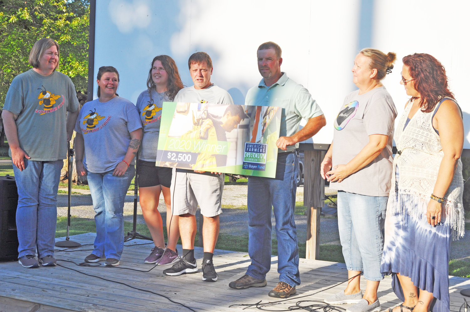 Waveland Strong President Troy Phillips, fourth from left, speaks during a ceremony to accept a $2,500 donation from local resident Darren Simpson, fifth from left, Friday at the Waveland Town Park.