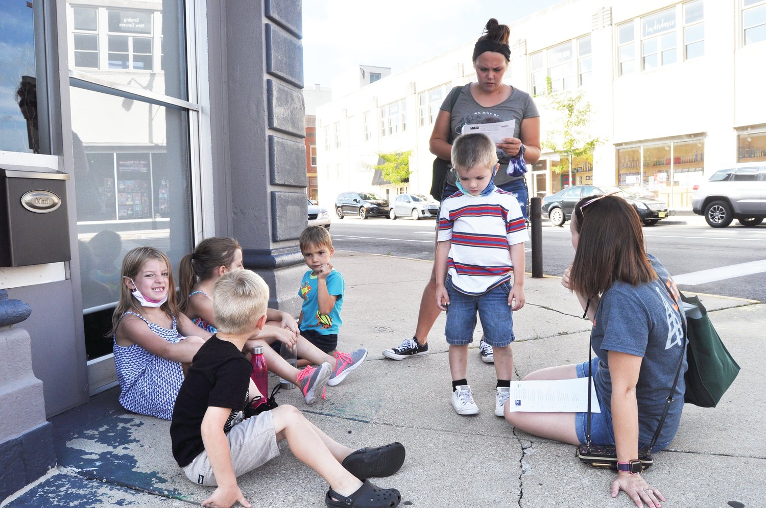 Chelsea Emberton checks the clues as Amber Wheeldon and, from left, Kartyr, Charlie, Boston, Kreed and Colt take a break during Athens Arts Gallery's Art Quest on Saturday in downtown Crawfordsville. The clues led to cultural attractions such as the Rotary Jail Museum and Speed Cabin.