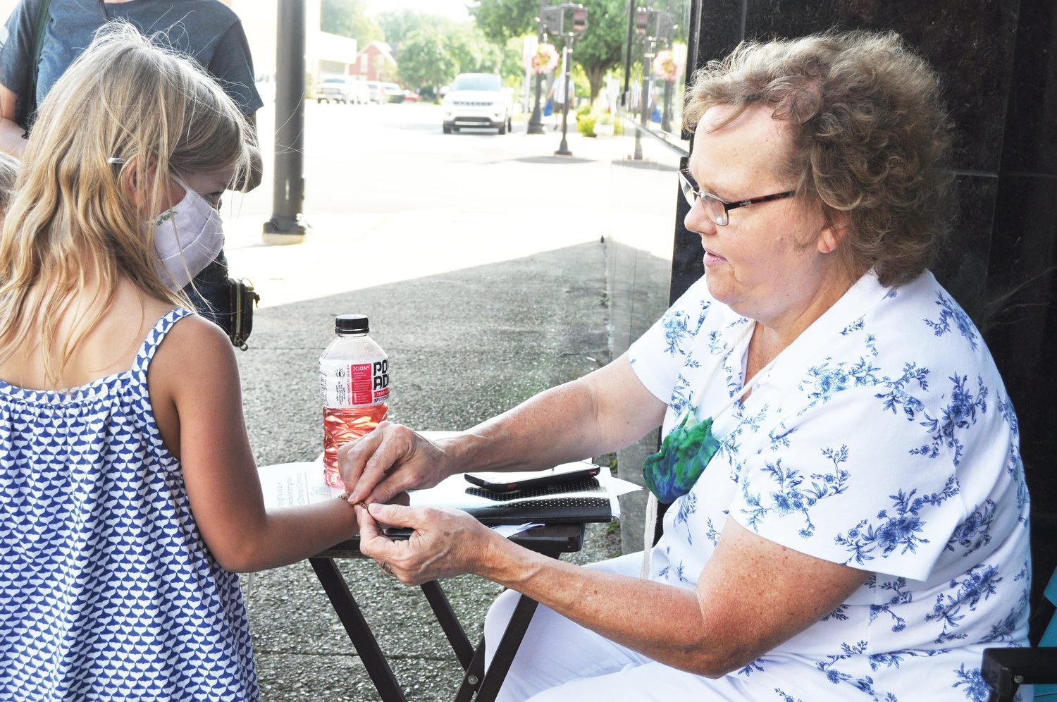 Cynthia McClure helps Charlie with a bracelet that was a prize for solving the clue for the Ben Hur Building in Athens Arts Gallery's Art Quest on Saturday in downtown Crawfordsville. The event is part of the gallery's 10th anniversary celebration.
