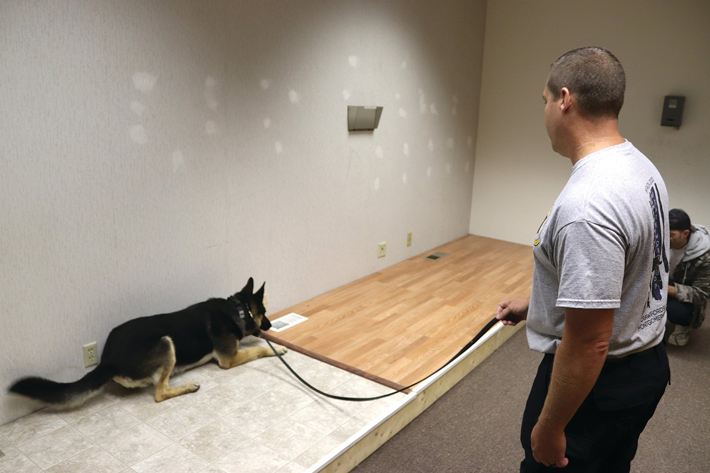 Sheriff's Deputy and Patrolman Michael Plant and his six-year-old K9 Partner Barrett check a room for hidden drugs Tuesday. Barrett has found the illegal items in the floor vent in a building owned by the city on Elmore Street. The building served as a K9 training facility this week for the North American Police Work Dog Association, which hosted its annual certification event in Crawfordsville this year.