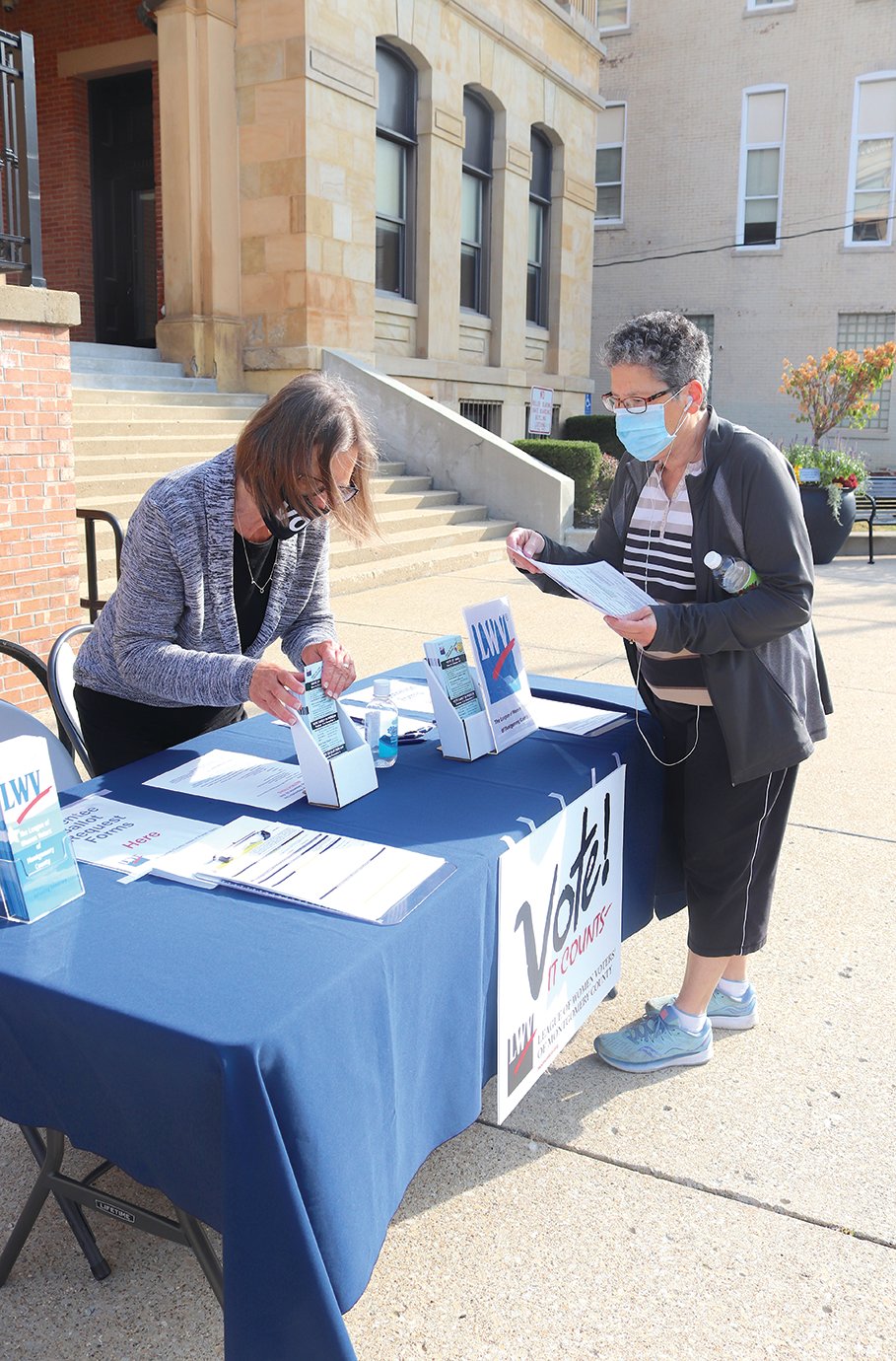League of Women Voters volunteer Helen Hudson assists Kathy Steele with absentee ballots Tuesday on Main Street outside the Montgomery County Courthouse. Steele was on her way to a long-term care facility in Crawfordsville to deliver the absentee ballots to residents.