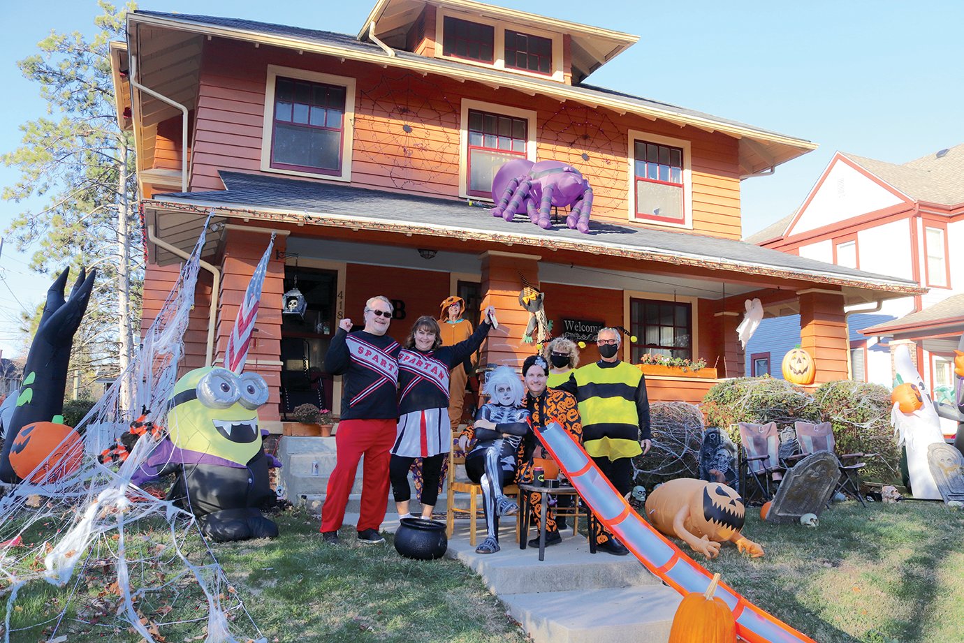 Spartan cheerleaders Kyle and Ashley Brown, left, open their festive home to friends, family and trick-or-treaters Saturday. The Browns were just one of many families on Main Street to transfer candy to visitors by chute.
