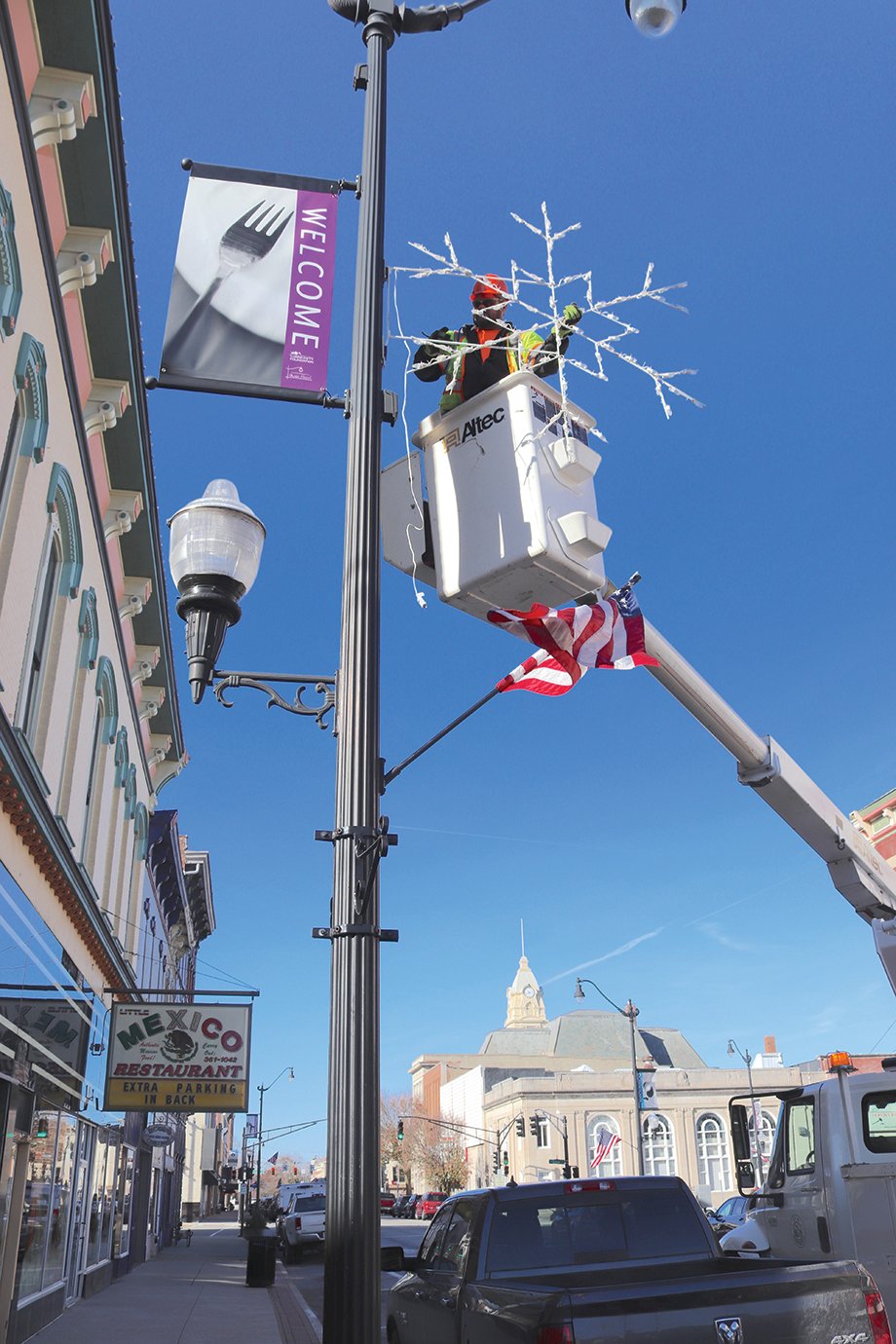 Tom Edwards with the Crawfordsville Street Department braves the bitter wind Tuesday morning to hang holiday decorations throughout downtown.