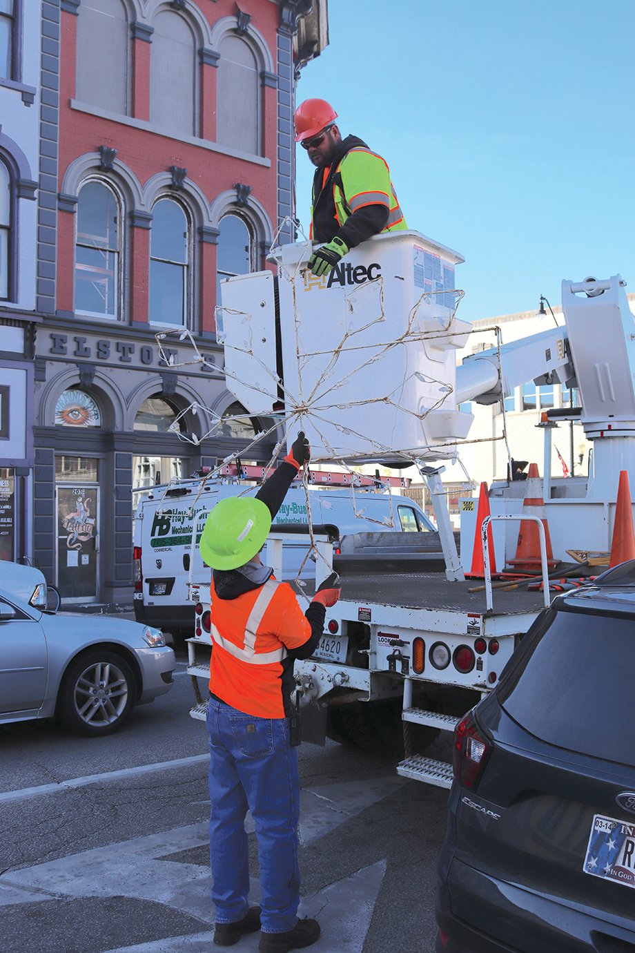 Crawfordsville Street Department crew member Ed McGaughey lifts the next holiday snowflake to Tom Edwards along Main Street Tuesday morning.