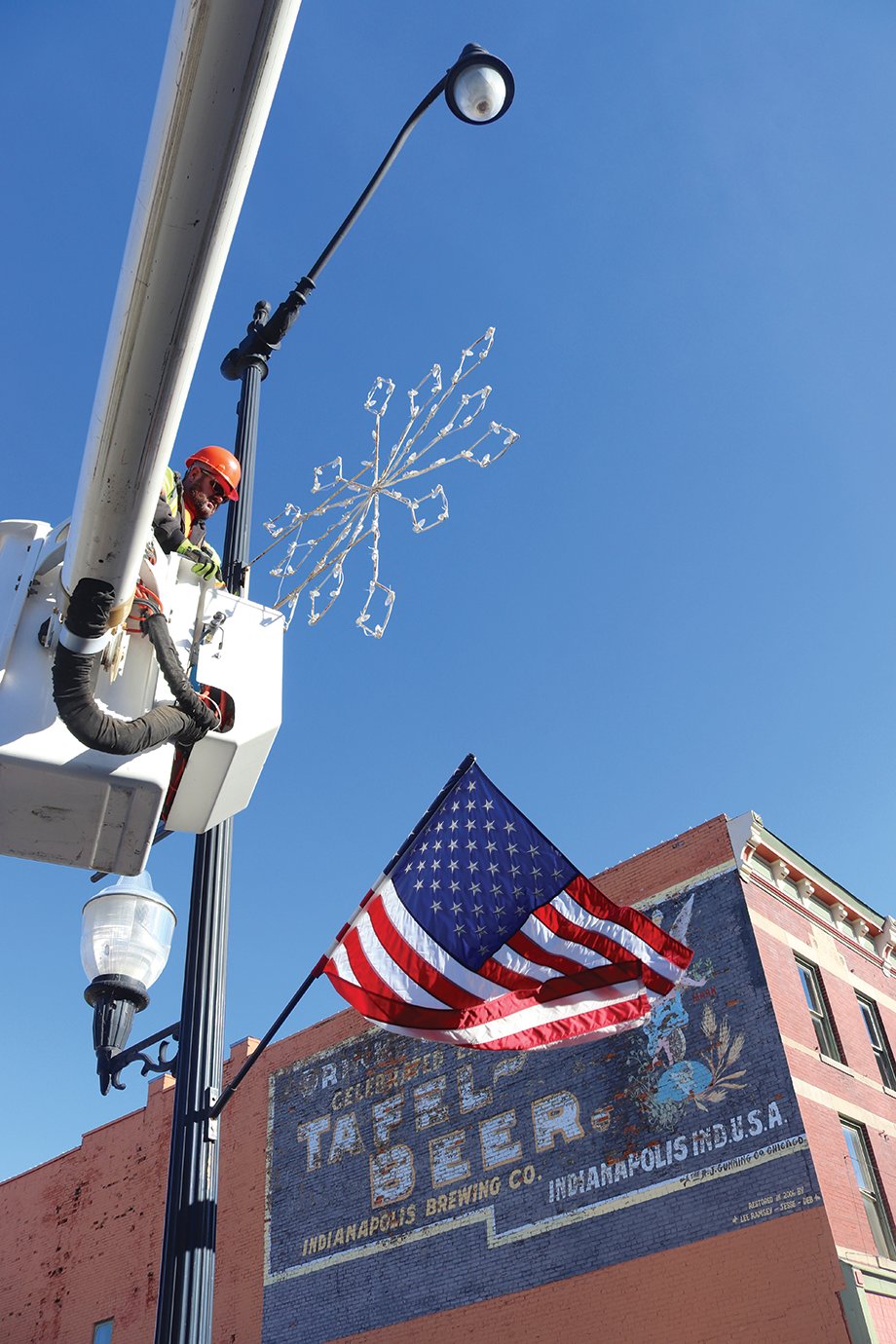 City employee Tom Edwards completes the installation of a holiday snowflake onto the side of a Main Street light pole Tuesday in downtown Crawfordsville.