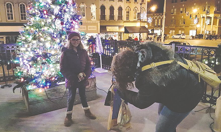 Nina Cunningham takes a photo of Shylee Stewart in front of the Christmas tree at the Montgomery County Courthouse during Downtown Party Night.