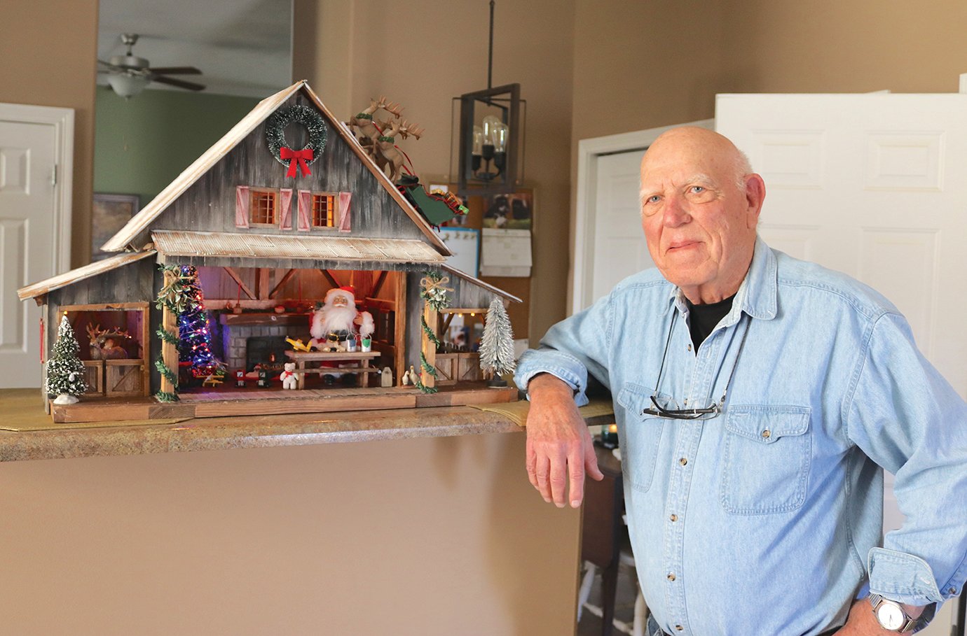 Eighty-two-year-old Richard Peterman proudly displays one of his latest creations Wednesday at his home; Peterman has been constructing miniaturized holiday homes, better known as Santa Houses, for nearly three decades for various organizations and businesses throughout Crawfordsville and Montgomery County.