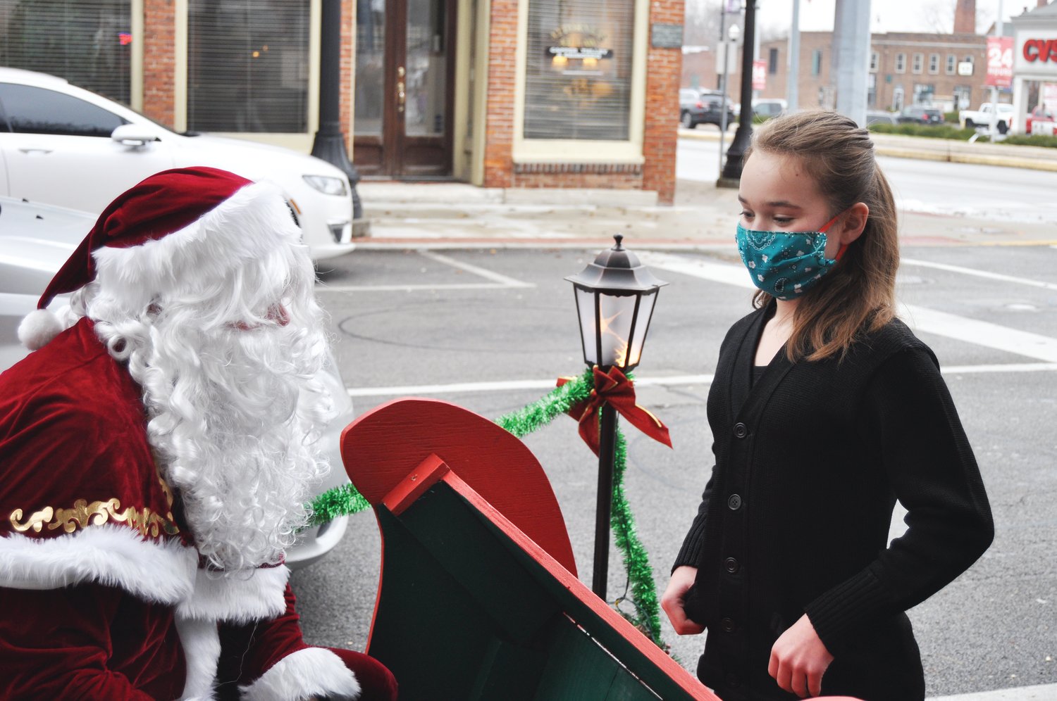 Acelyn Starcevich, 10, gives her wish list to Santa at Brothers Pizza Company on Saturday. St. Nick came to the restaurant with his elves and a reindeer to visit children, who could walk up to his sleigh or deliver their lists from the car. Children received a toy and a CD featuring music from local artists.