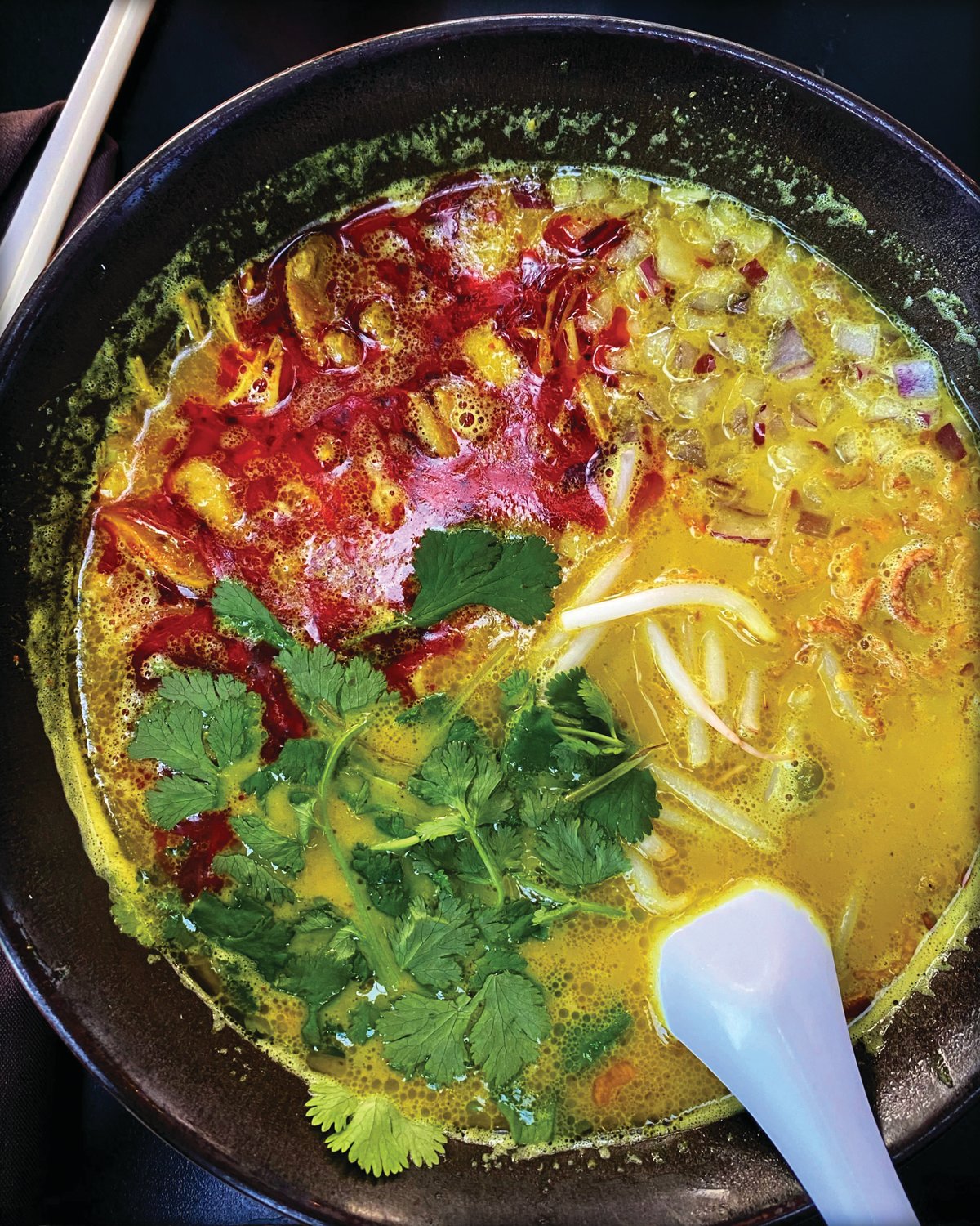 Khao Poon is a traditional Lao soup with red curry and rice noodles, fragrant with lemongrass and coconut.