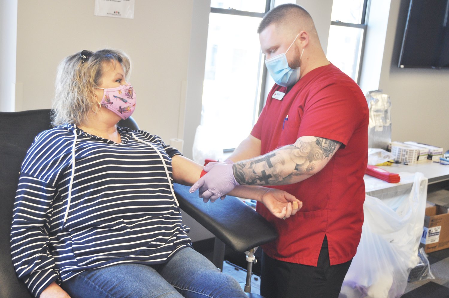 Austin Benson of the American Red Cross puts a tourniquet on Jennifer Weir after she gave blood in a blood drive sponsored by the Montgomery County Leadership Academy at Fusion 54 Friday.