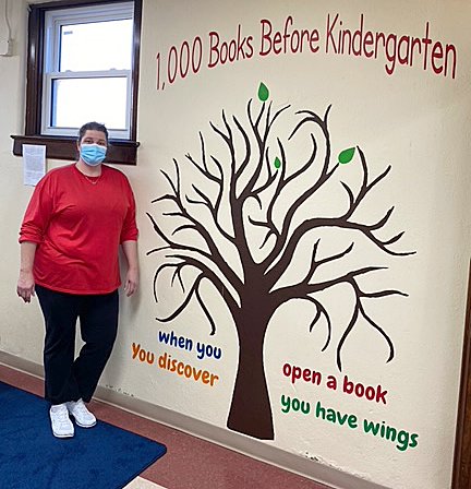 Bunny Sutton poses with the mural she created for the children’s area of the Linden Public Library.