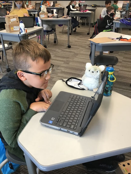 A Sugar Creek Elementary third grader uses a laptop computer with his Purrble nearby. The battery-powered stuffed animals are designed to help calm students.
