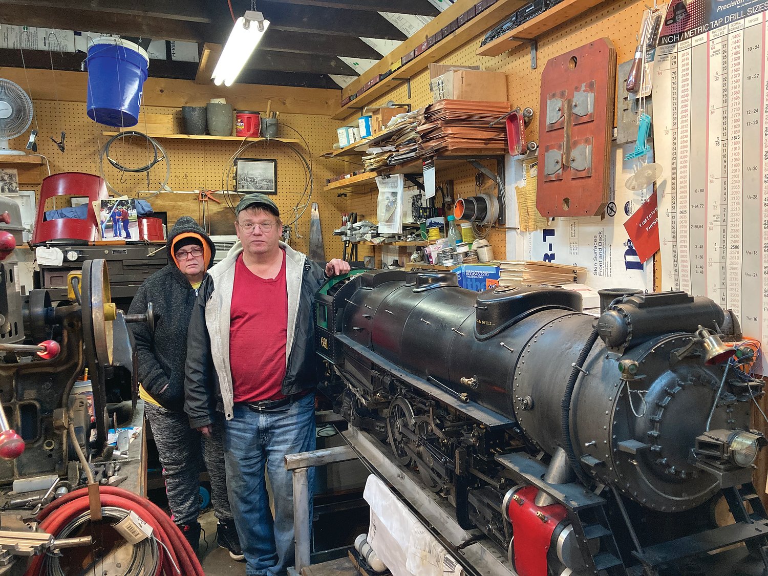 Tim Sering and his wife, Deb, stand next to a model steam engine in his workshop at their Darlington home. The engine is a replica of a locomotive used on the Nickel Plate Railroad.