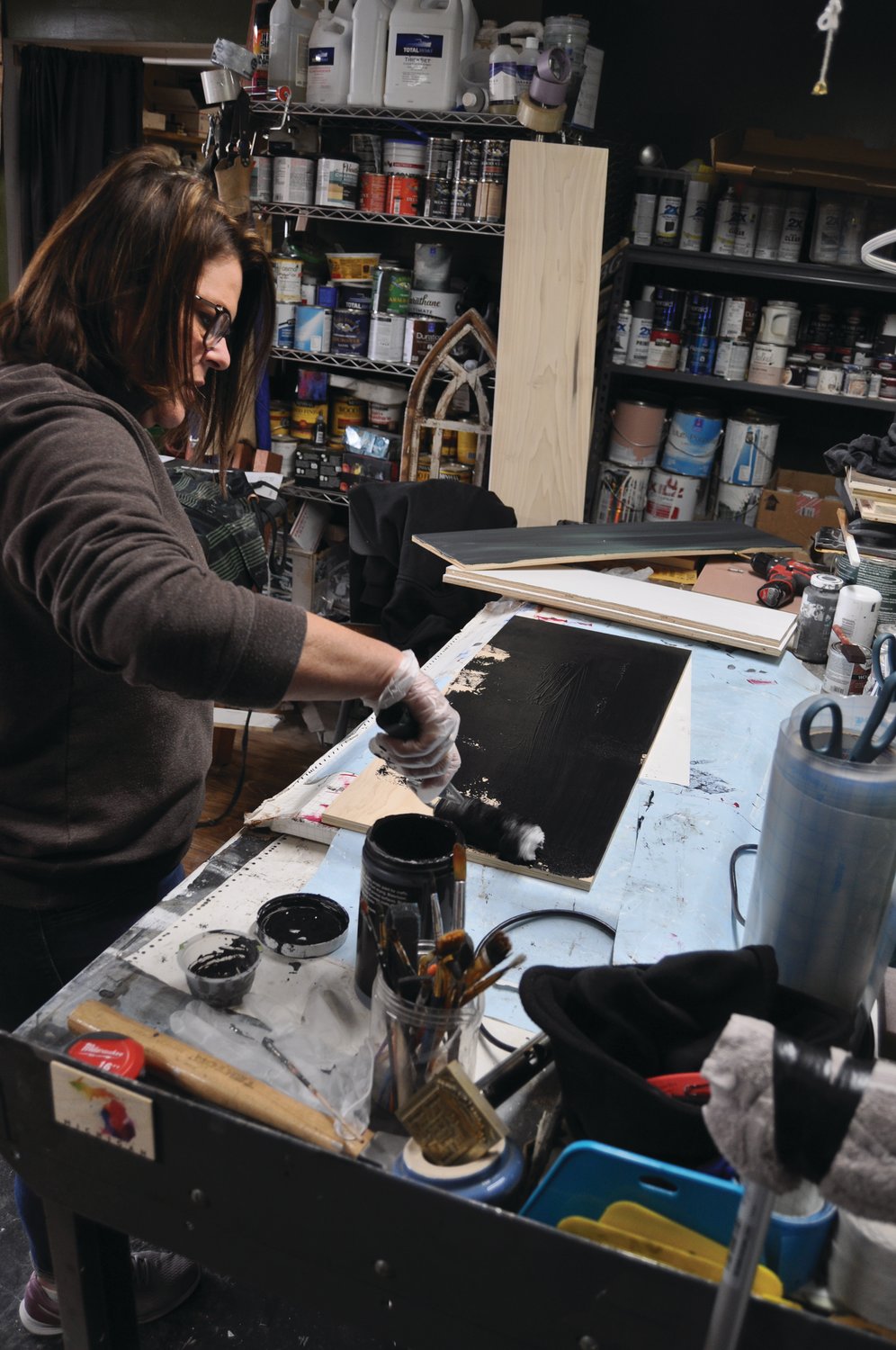 Jami Harrington, owner of Reclaimed by Grace, paints a board at the shop Tuesday. Fusion 54 is seeking funding for an entrepreneur program and small business development and support.