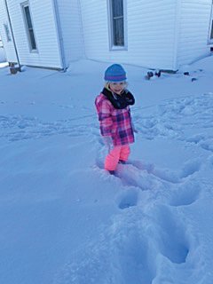 Adalyn Hayes watches her older sister Emery play in a snow drift Tuesday.