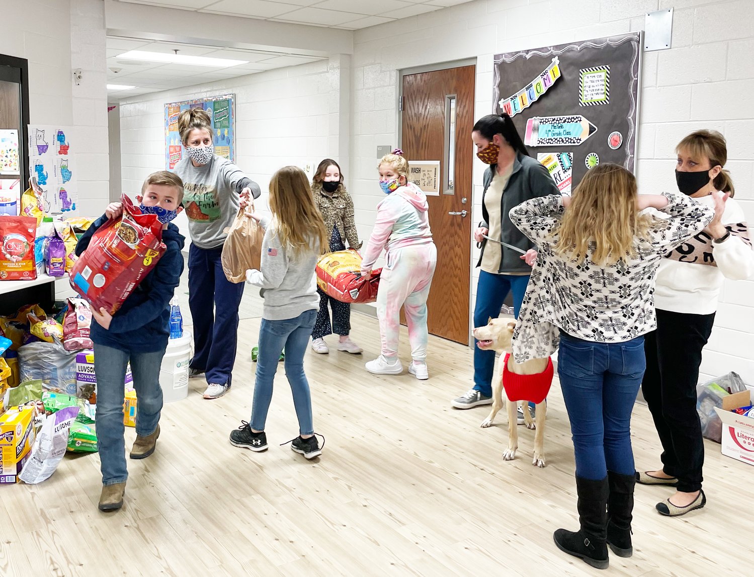 Misha Anderson, second from left, hands a bag of pet supplies to a student at Hoover Elementary Monday. The school