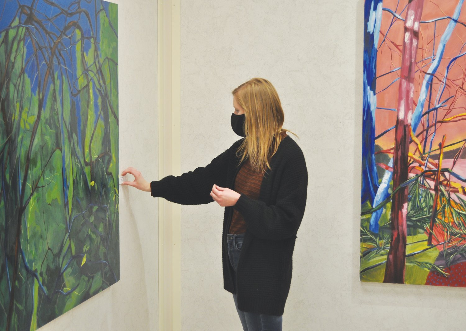 Caitlyn Brandt places a title card next to one of her paintings at the Crawfordsville District Public Library