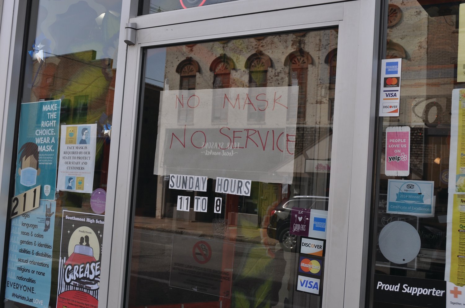 A sign notifying customers of the mask order hangs in the window at Little Mexico Tuesday morning. The sign was removed later in the day.
