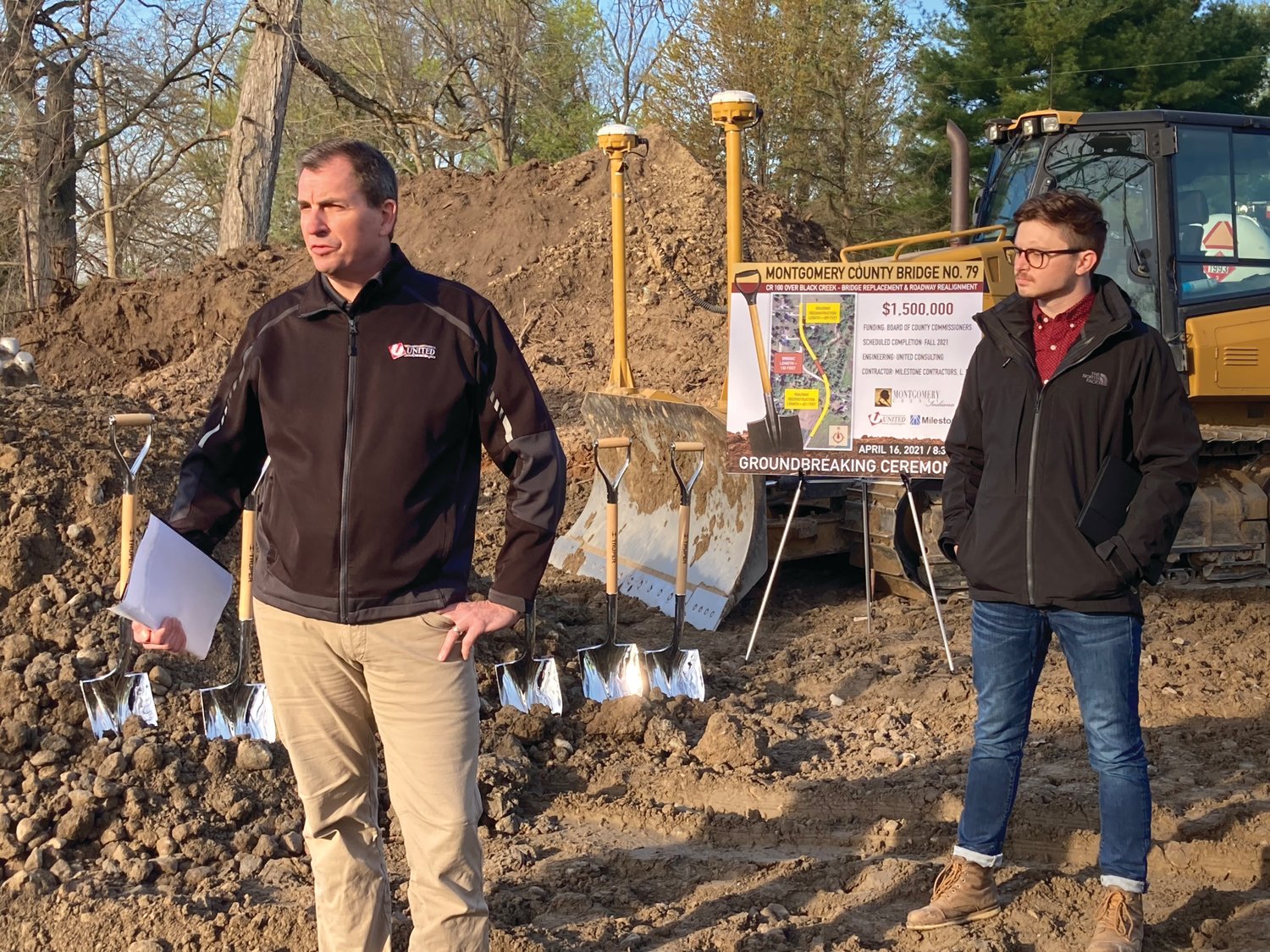 Jon Clodfelter, left, United Consulting bridge department manager, speaks at a groundbreaking ceremony for the C.R. 100W bridge replacement and roadway realignment project as bridge design engineer Bradley Salpietro looks on Friday at the construction site.