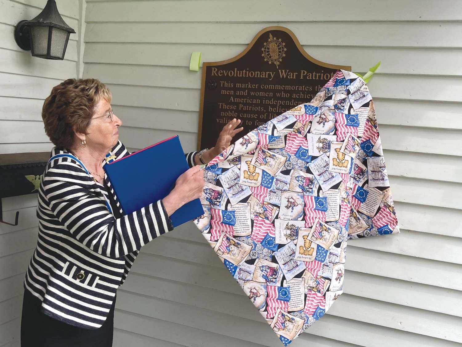 Charlotte Blair, Indiana State Daughters of the American Revolution regent, unveils a plaque honoring Revolutionary War veterans at the Elston Memorial Home on Saturday. The plaque is part of DAR
