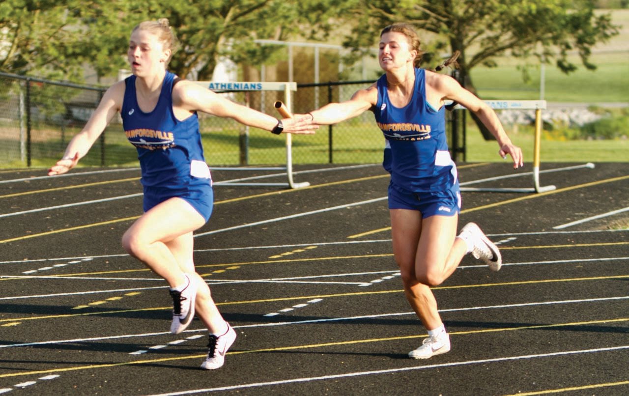 Crawfordsville’s Shea Williamson hands the baton off to Parker Hartman in the last leg of the 4X100 meter relay won by the Athenians.