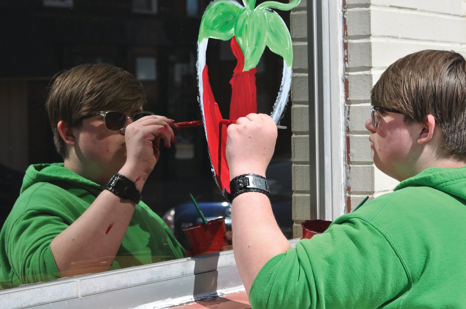 Carsen McCoy paints a strawberry on the Weemickle Building in downtown Crawfordsville Saturday. The yearly tradition promotes the Strawberry Festival, which runs from June 11-13 on the grounds of the Lane Place.