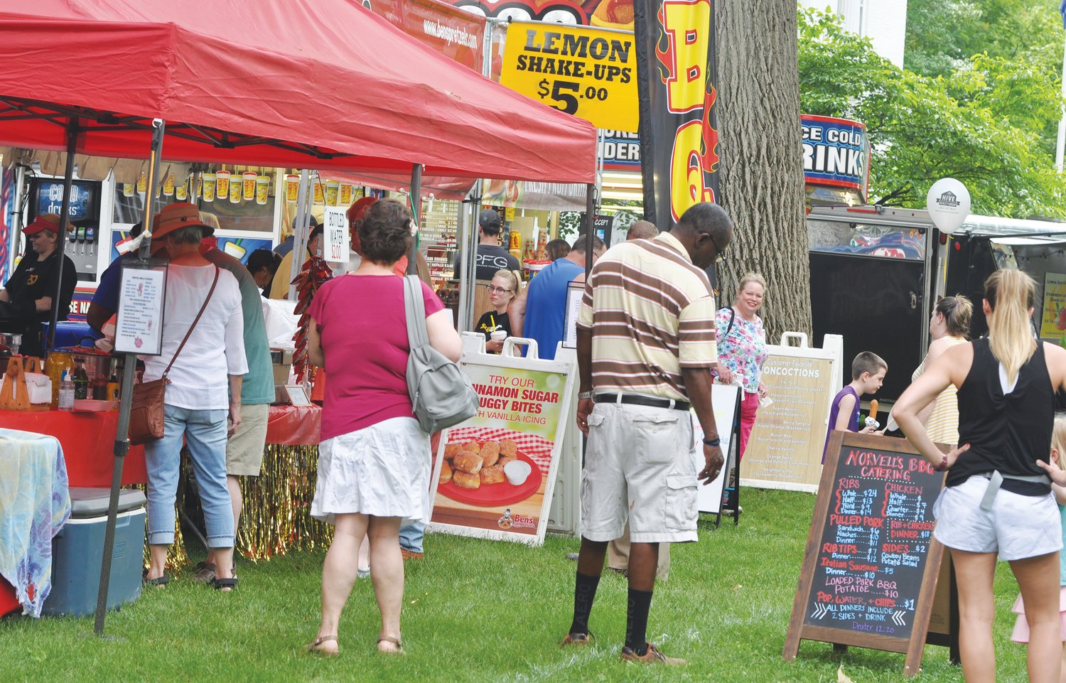 ABOVE: People look at the menu for Norvell’s BBQ booth Friday at the Strawberry Festival. The festival has done away this year with the ticket booth for the food area. Vendors are accepting cash and/or credit and debit cards.
