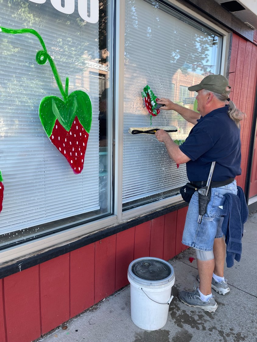 Kenn Clark removes a painted strawberry from Brothers Pizza.