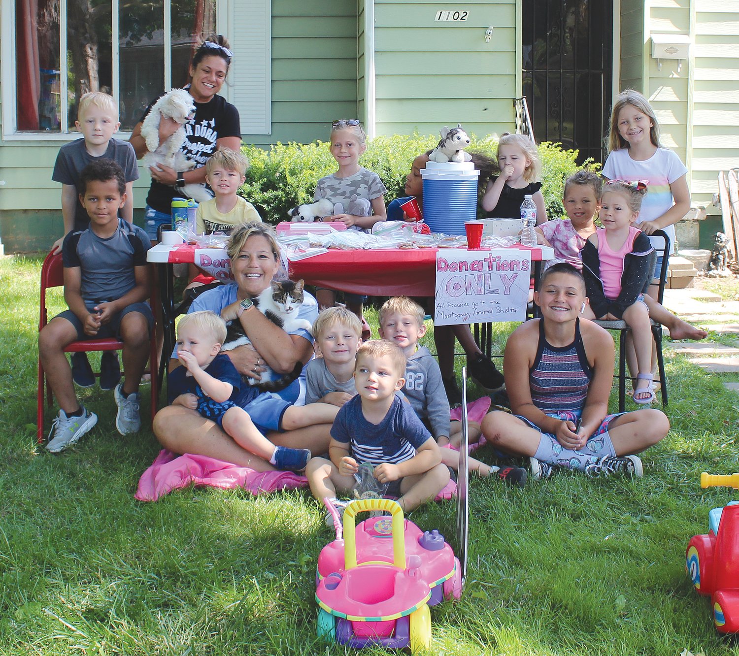 Colleen Abston (holding Milo the cat) poses with her day care children at 1102 Lane Ave. The group set up a lemonade and cookie stand Thursday to raise funds for the Animal Welfare League of Montgomery County. Abston said they chose the fundraiser as a way to say thank you to the AWL after Milo went missing for nearly two weeks. Abston contacted the AWL when he didn’t return home and they shared his photo. When he was eventually found near the Twin Oaks subdivision earlier this week, he was taken to the shelter and they knew who to contact. Abston and the children are grateful to have Milo home.