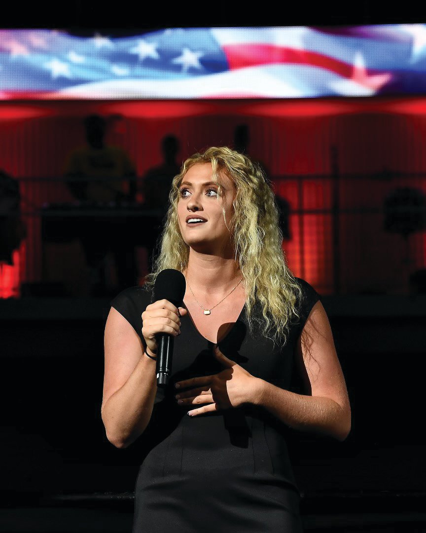 Tori Wilkinson sings the national anthem at the Pacers game in May behind a screen displaying the American flag.