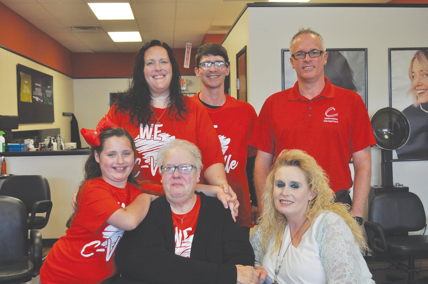 Debra Raye, center of front row, poses with members of her family at Cost Cutters. A fundraiser for the local cancer patient is planned for 1-6 p.m. Sunday at the salon. Also pictured is stylist Debbie Wright (in white) and Cost Cutters manager Fred Punke (back row, right).